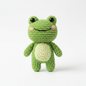 Crocheted green frog stuffed animal on white background