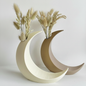 Two crescent moon vases on white background, one cream and one tan, with dried pampas grass