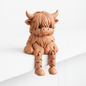 Cute 3D printed articulated highland cow figurine with fluffy fur and dangling legs on white background
